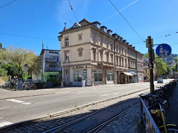 Historisches Eckhaus an Straßenbahnstrecke, Fahrräder und Stadtstraße bei Sonne